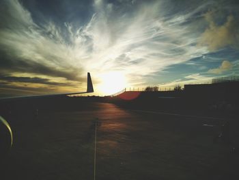 Airplane on airport runway against sky during sunset