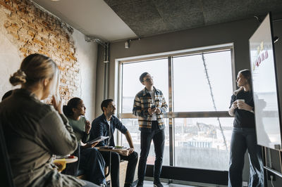Young female programmer taking team meeting in tech startup office