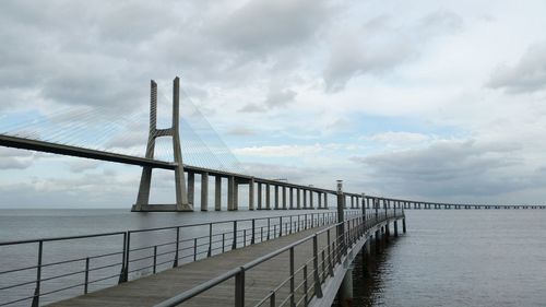 Pier on sea against cloudy sky