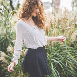 Side view of woman standing on field looking down