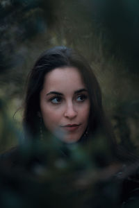 Portrait of beautiful young woman against trees
