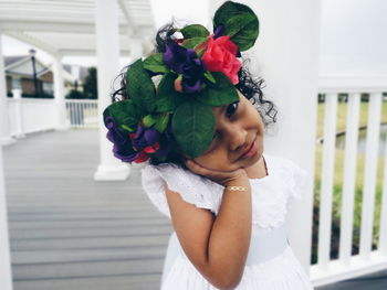 Portrait of girl wearing flower wreath with head cocked