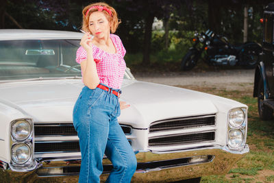 Portrait of young woman standing in car