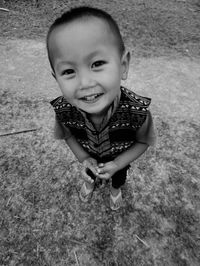 High angle portrait of smiling cute boy standing on field