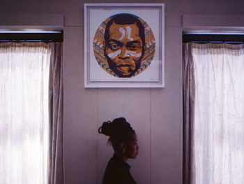 Portrait of woman standing against window at home