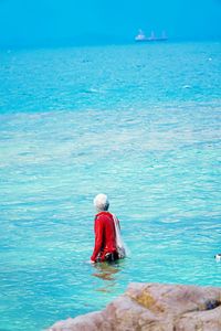 Rear view of man in sea against blue sky