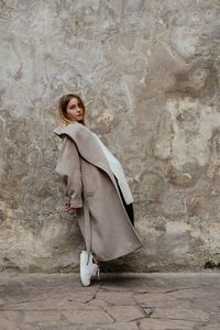 Portrait of woman standing against wall