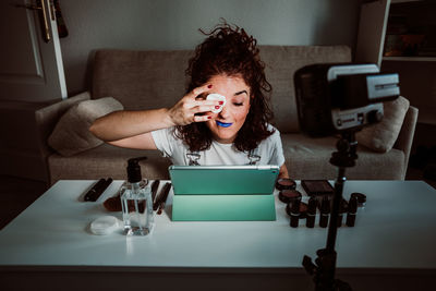 Young woman using tablet while sitting on table