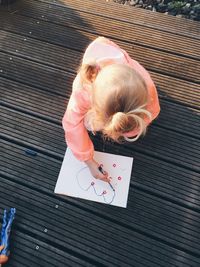 High angle view of girl making drawing in book on table