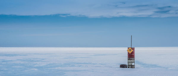 Lifeguard hut on snow covered land against sky