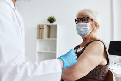 Doctor vaccinating senior woman at hospital
