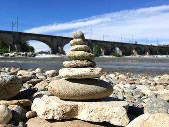 Stack of pebbles on shore against sky
