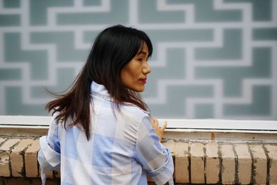 Young woman standing against white wall