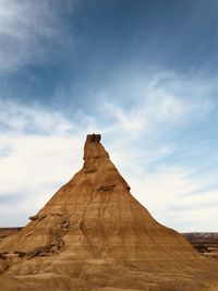 Rock formations on landscape against cloudy sky