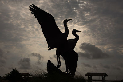 Low angle view of silhouette statue against sky