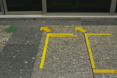 High angle view of yellow arrow sign on road