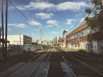 Railway tracks in city against sky