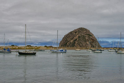 Sailboats moored in sea against sky