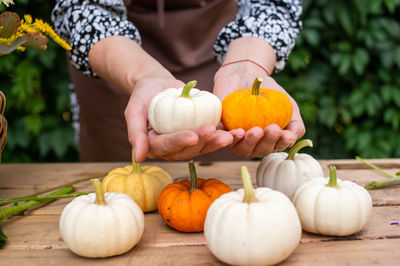 White, orange and yellow pumpkins are on the table and in the hands