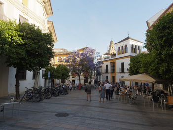 People on street amidst buildings in city against sky