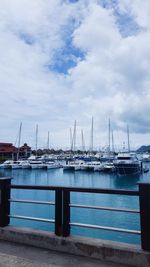 Boats moored at harbor against sky