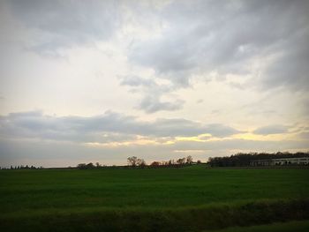 Scenic view of grassy field against cloudy sky