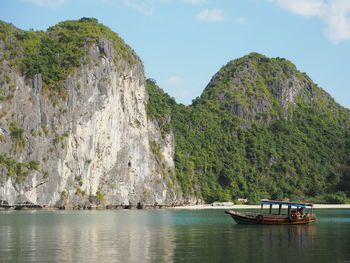 Boat on halong bay by rocky mountains