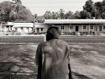 Rear view of man sitting on sidewalk in city