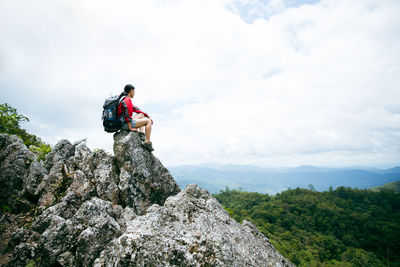 Low angle view of man standing on rock against sky