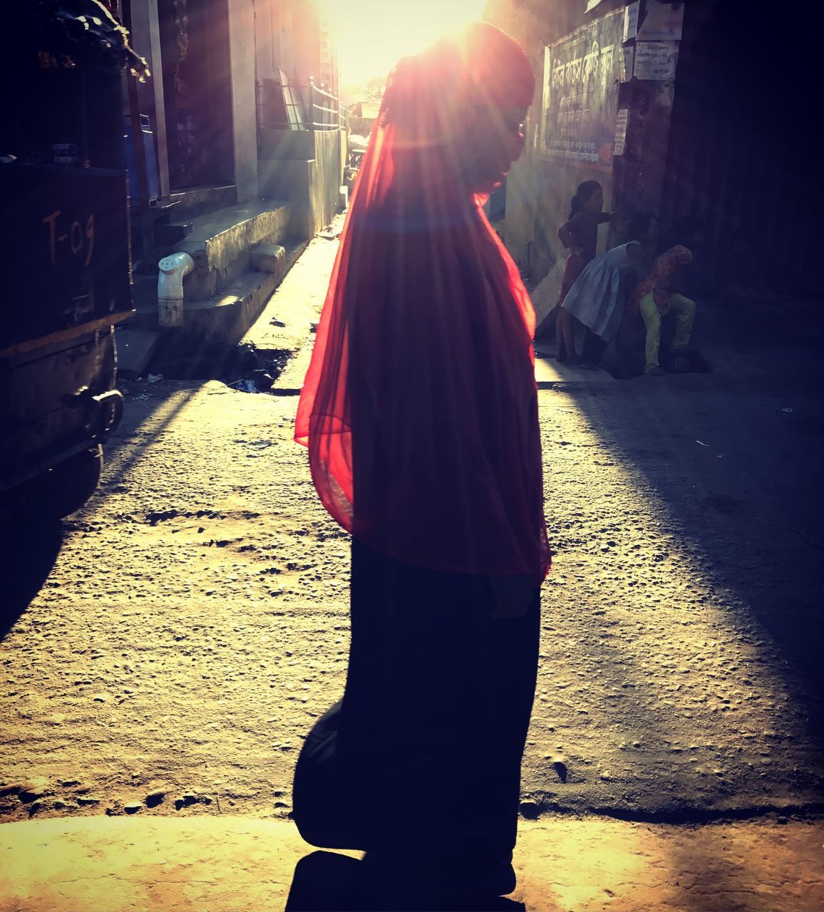 rear view, real people, street, one person, walking, full length, outdoors, standing, women, lifestyles, building exterior, sunlight, city, road, built structure, day, men, architecture, sari, adult, people