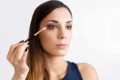 Fashion model applying make-up against white background