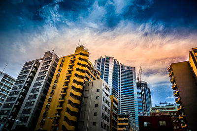 Low angle view of skyscrapers against cloudy sky