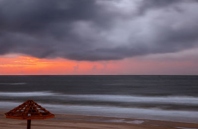 Scenic view of sea against dramatic sky during sunset