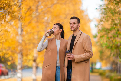 Woman holding autumn leaf against tree