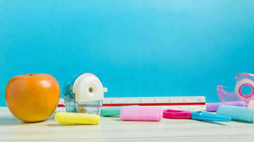 Close-up of school supplies on table against blue background