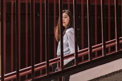 Portrait of woman standing against railing