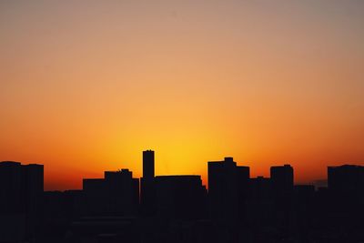 Silhouetted cityscape against orange sky