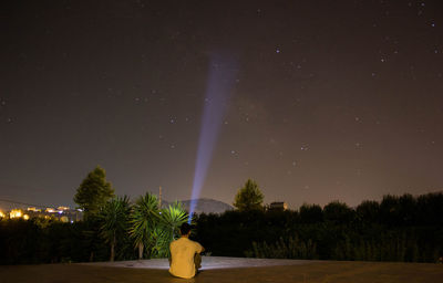 Rear view of man sitting outdoors at night