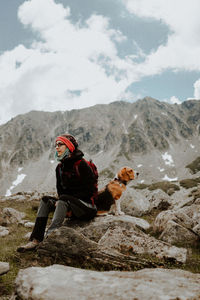 Girl sitting on rock against mountains with her beagle dog