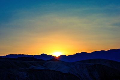 Scenic view of silhouette mountains against clear sky at sunset