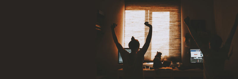 Silhouette man standing by window at home