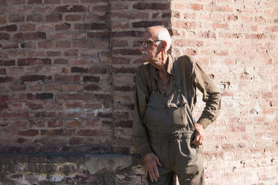 Portrait of old man against bricked wall