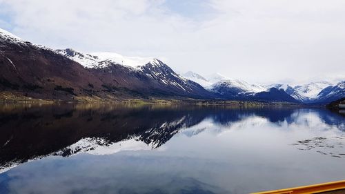 Scenic view of lake by snowcapped mountains against sky