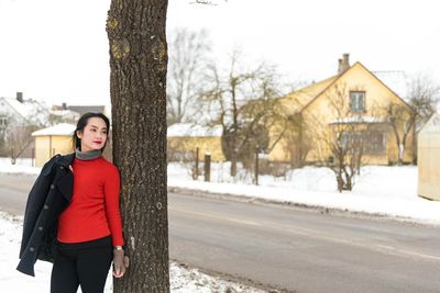 Woman standing by tree in city during winter