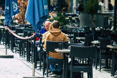 Rear view of people sitting on chair at street