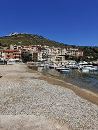 Sailboats moored on beach by buildings against clear sky