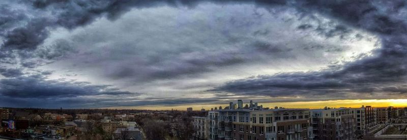 Cityscape against cloudy sky at sunset