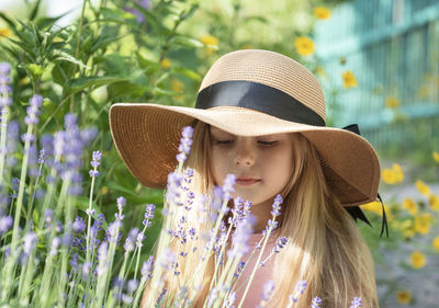 Little girl in a straw hat surrounded by lavender flowers. 