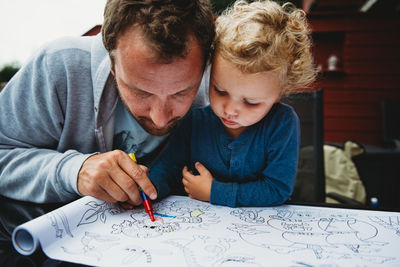 Father and young son coloring outside during covid quarantine