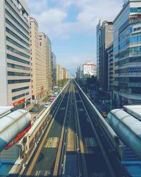 Railroad tracks in city against sky